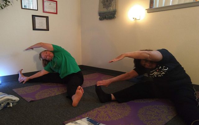 Two middle-aged women practicing on a yoga mat in the Namaste Wellness Detroit studio.